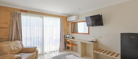Une chambre d’hôtel comprenant un lit, un bureau, une télévision et un coin salon.