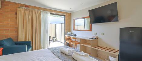 A hotel room with a bed, a desk, a television, and a window with curtains.