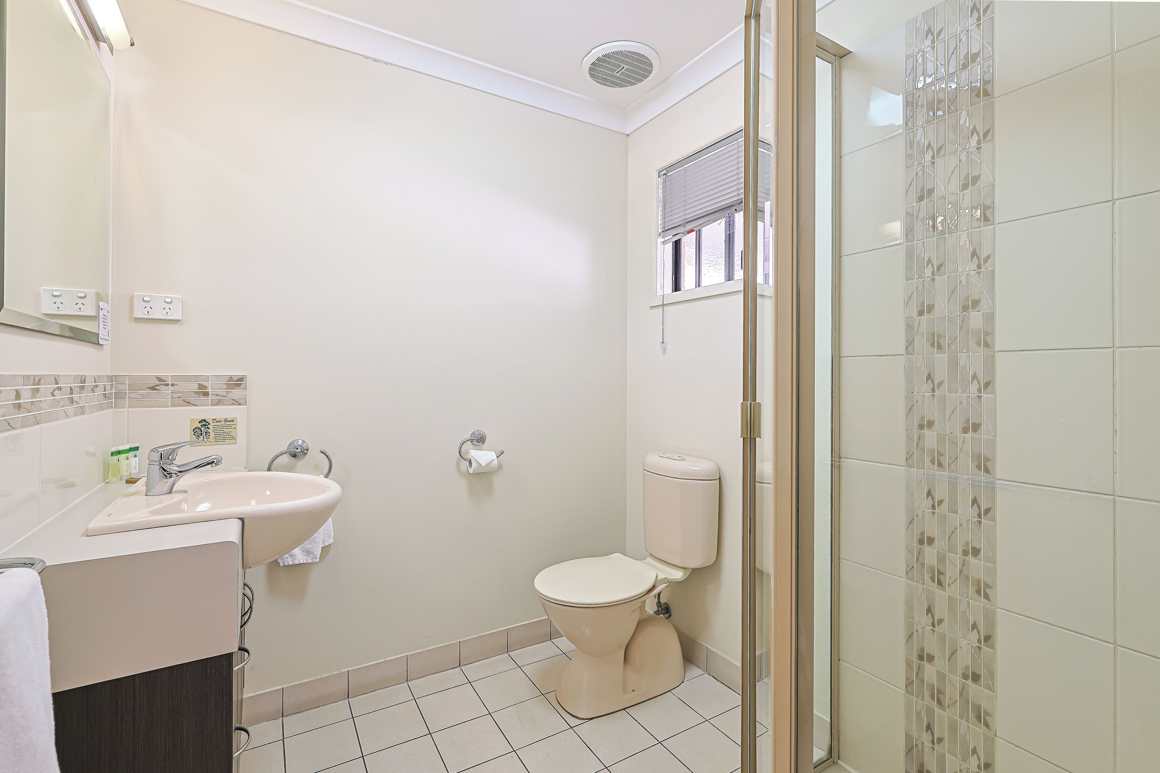 A bathroom with a toilet, sink, and shower area.