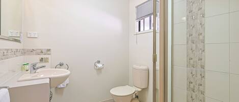 A bathroom with a toilet, sink, and shower area.