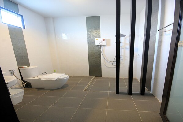 A modern bathroom with a bathtub, toilet, and shower area.