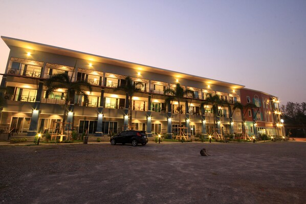 Un hotel de varios pisos con balcones, una zona de estacionamiento y una fachada bien iluminada.