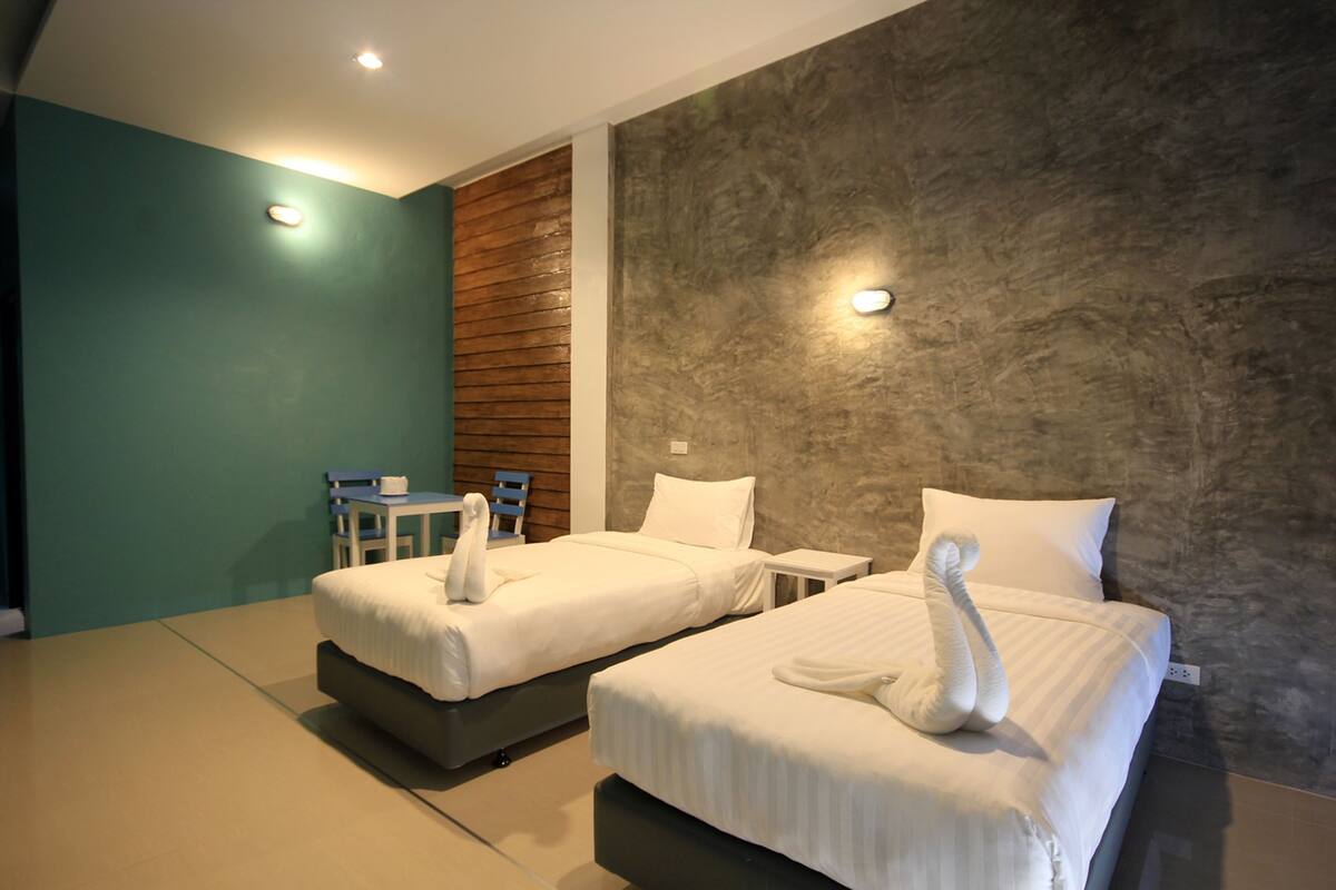 A hotel room with two beds, a small table, and a chair.