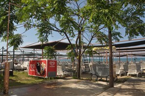 A beachside area with sun loungers, a covered seating area, and a sign advertising a hotel.