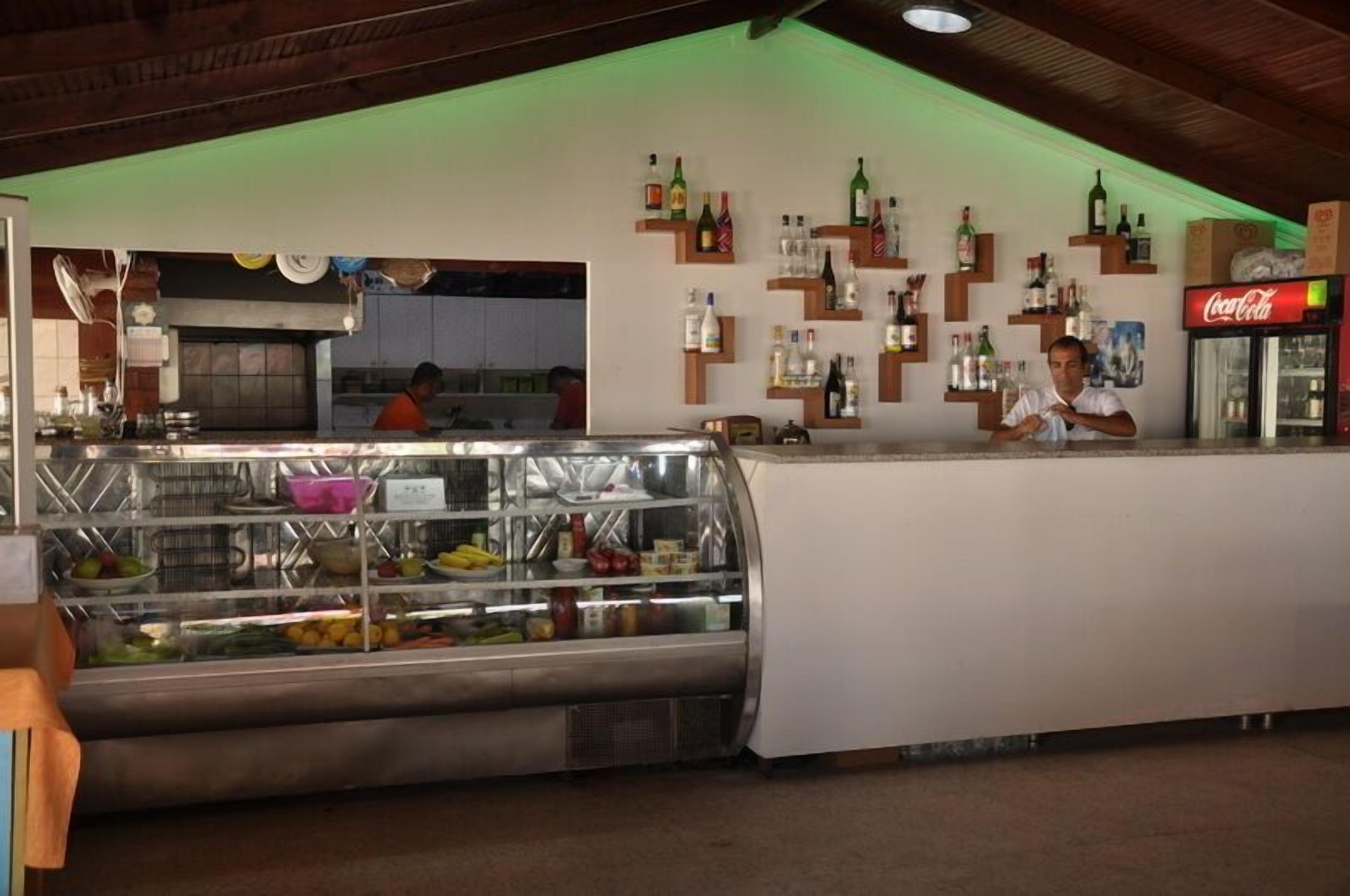 Una zona de bar con una vitrina llena de frutas y un refrigerador de Coca-Cola.