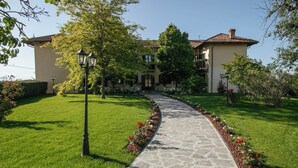 Un chemin de pierres mène à un bâtiment doté d’un toit en tuiles et d’une pelouse bien entretenue.