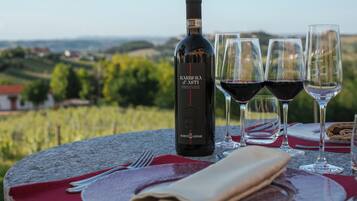 A bottle of wine and glasses on a table with a red napkin and a folded napkin, set against a scenic vineyard backdrop.