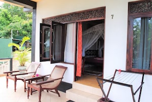 A balcony with a wooden table and chairs, a drying rack, and a partially open door with a curtain.