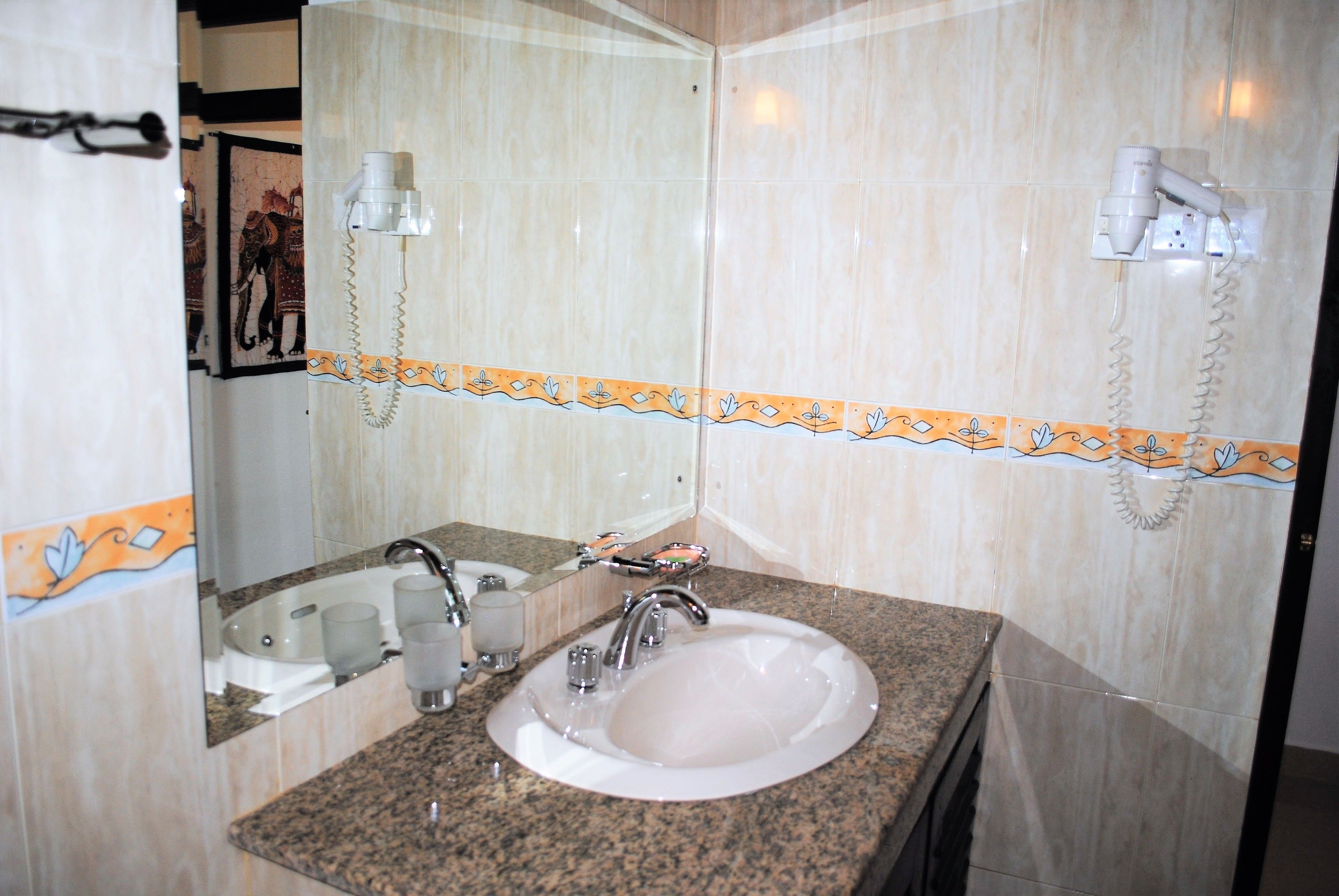 A bathroom with a granite countertop sink, a mirror, and a towel rack.