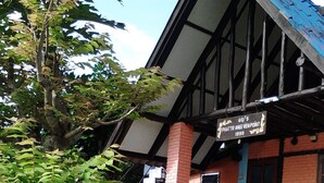 A building with a brick facade, a sign indicating '60/5 PHATR ANCE VIENPOINT 1999', and a staircase leading to a covered area with outdoor seating. - View Point Lodge (Mae Hong Son)