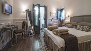 A hotel room with a bed, bedside table, chair, and a television on the wall. - Il Giardino d'Ulisse (Reggio Calabria)