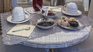 A dining table set with various dishes, a pitcher of red drink, and a vase with flowers. - Il Giardino d'Ulisse (Reggio Calabria)