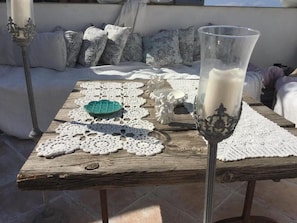 Uma mesa de madeira com um castiçal de vidro e um jogo de crochê.