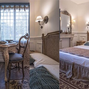 Quarto com escrivaninha de madeira, cadeira e cama com cabeceira. Há uma janela com cortinas, luminária na parede e um espelho.