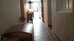 A hallway with a wooden bench, tiled floor, and framed pictures on the walls. - Casa di Alfredo (Siena)