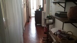 A narrow hallway with a tiled floor, a radiator, and a shelf with books and a basket. - Casa di Alfredo (Siena)