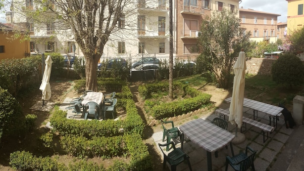 A courtyard with outdoor seating, a tree, and a building in the background. - Casa di Alfredo (Siena)