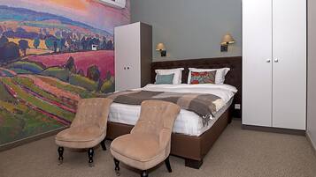 Un dormitorio con cama, dos sillas, un cuadro grande y un armario.