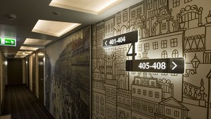 Un pasillo de hotel con señales de indicaciones y un mural de edificios.