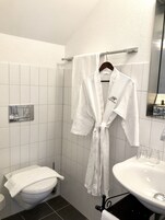 A bathroom with a toilet, sink, and a robe hanging on a rack.