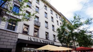 Un hôtel à plusieurs étages, doté d’une façade classique, de balcons et d’une enseigne indiquant « HÔTEL TOWNHOUSE ».