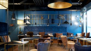 Un intérieur moderne avec un canapé bleu recouvert de tissu, des fauteuils en cuir et divers modèles de tables et de lampes.