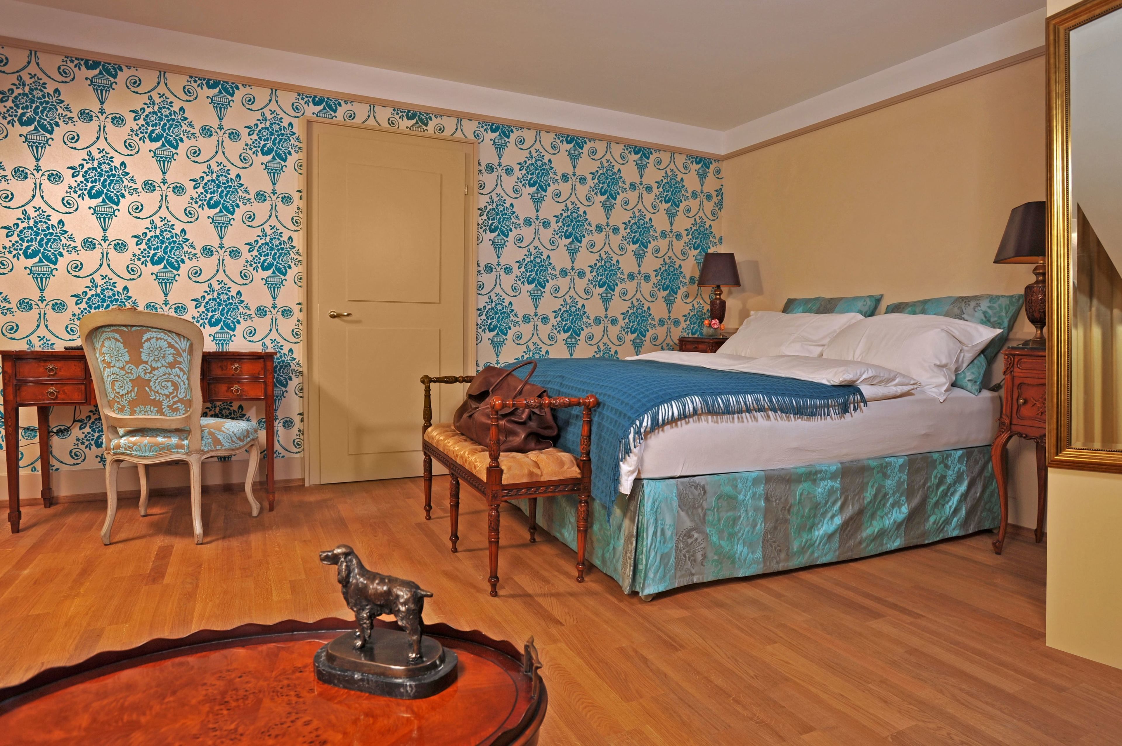 Un dormitorio con cama, una silla, cómoda y lámpara.