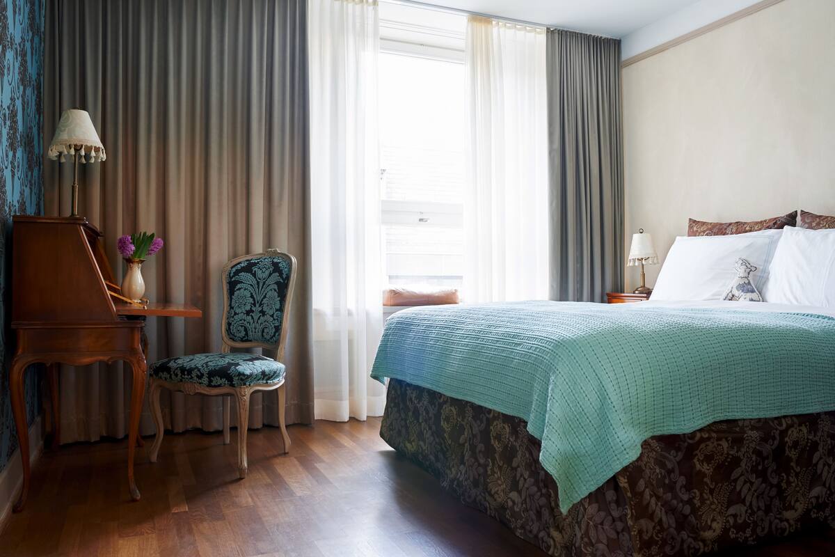 Ein Hotelzimmer mit Bett, Stuhl, Tisch und Lampe.