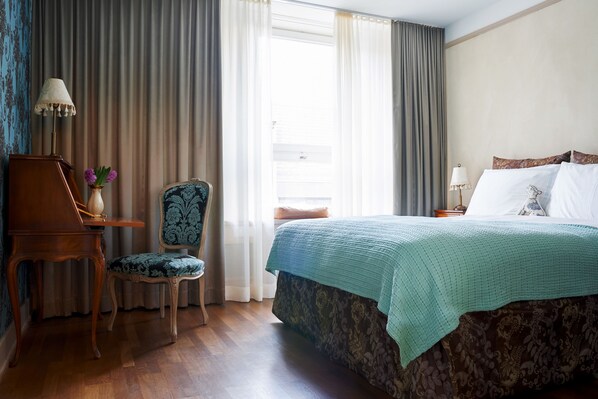 Una habitación de hotel con una cama, una silla, una mesa y una lámpara.