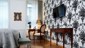 Une chambre à coucher comprenant un lit, un bureau avec une chaise, une télévision et un papier peint à motifs.