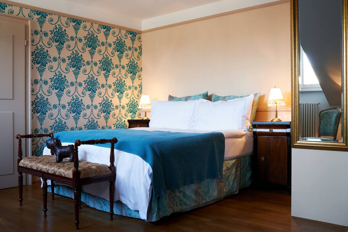 Ein Schlafzimmer mit einem Bett, Nachttischen, einem Sessel und einem Spiegel.