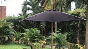 A patio with a table and chairs, surrounded by lush greenery and palm trees. - Joy Family Lodge (Amasaman)