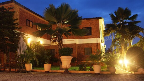A courtyard with a brick building, potted plants, and outdoor seating. - Joy Family Lodge (Amasaman)