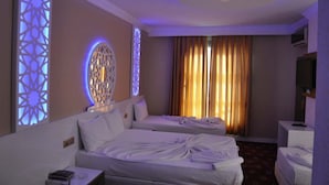 A hotel room with two beds, a ceiling light, a TV, and a decorative wall panel. - Ugur Hotel (Mersin)