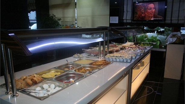 A buffet with various food items and a television screen in the background. - Ugur Hotel (Mersin)