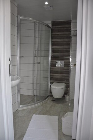Un baño moderno con cabina de ducha de vidrio, inodoro y lavamanos.