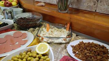A buffet table with various dishes including olives, ham, and a salad.