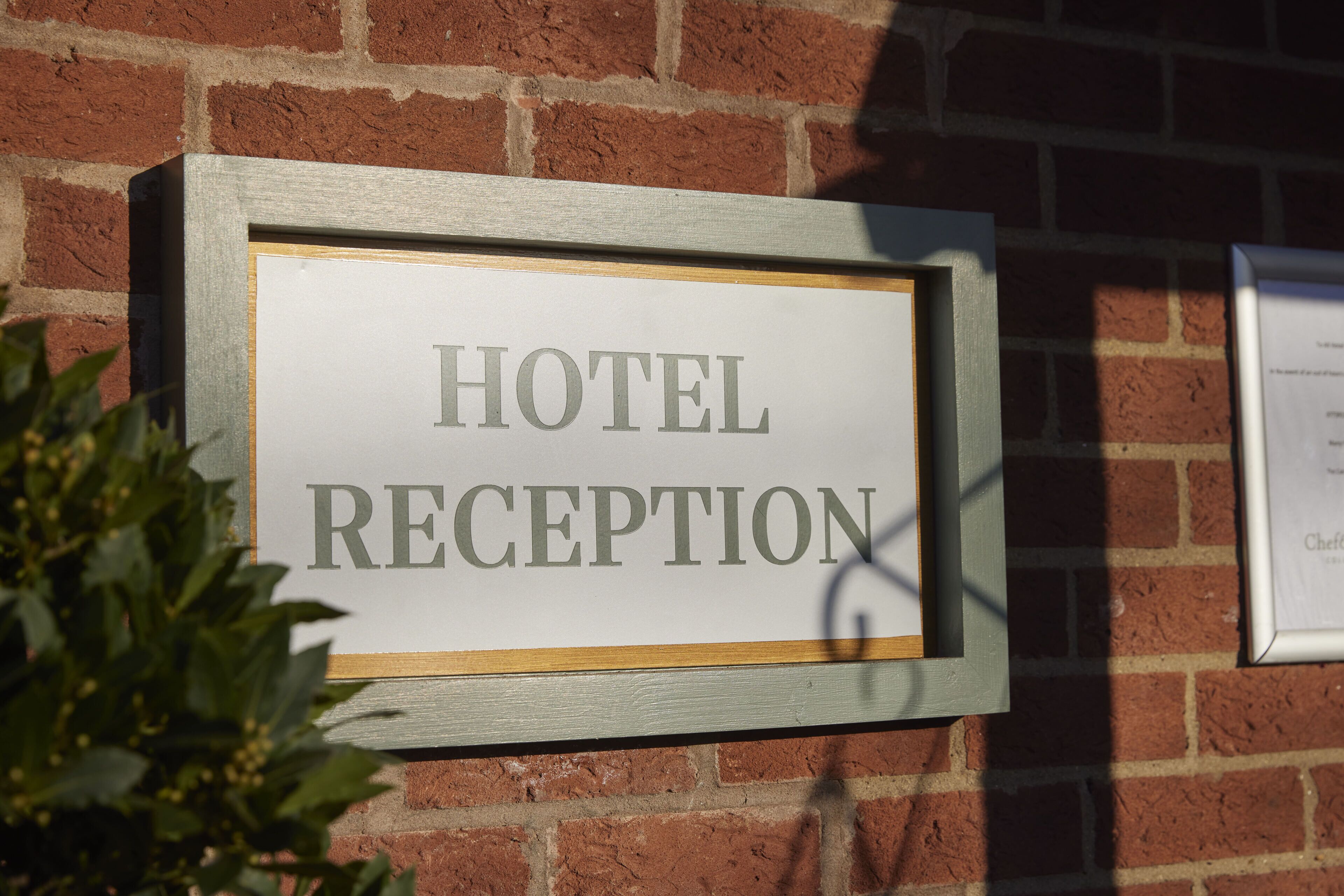 A sign with the words "HOTEL RECEPTION" on a brick wall.
