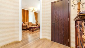 Una habitación con puerta de madera, un candelabro y una zona de estar con sofá y mesa de centro.