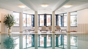 A spacious indoor swimming pool with clear reflections, large windows, and a potted plant. - Gut Wenghof - Family Resort Werfenweng (Werfenweng)