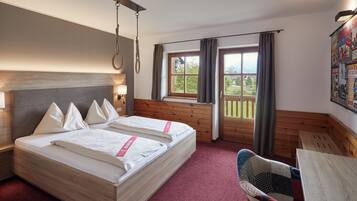 Une chambre d’hôtel avec deux lits, une tête de lit en bois, une fenêtre avec des rideaux, une vue sur la verdure et une lampe fixée au mur.