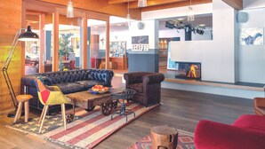 A spacious living area with a fireplace, wooden ceiling beams, and a large sofa. - Gut Wenghof - Family Resort Werfenweng (Werfenweng)