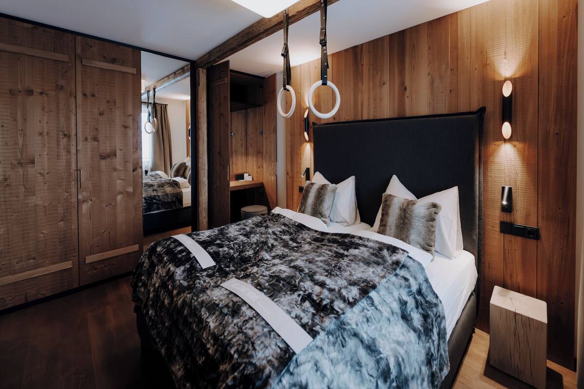 Ein modernes Schlafzimmer mit einem großen Bett, Holzwänden und einem Spiegel.