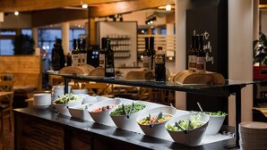 A buffet setup with various food bowls and bottles of wine on a counter. - Gut Wenghof - Family Resort Werfenweng (Werfenweng)