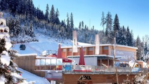 A ski resort building with a ski lift in the background, surrounded by snow-covered trees. - Gut Wenghof - Family Resort Werfenweng (Werfenweng)