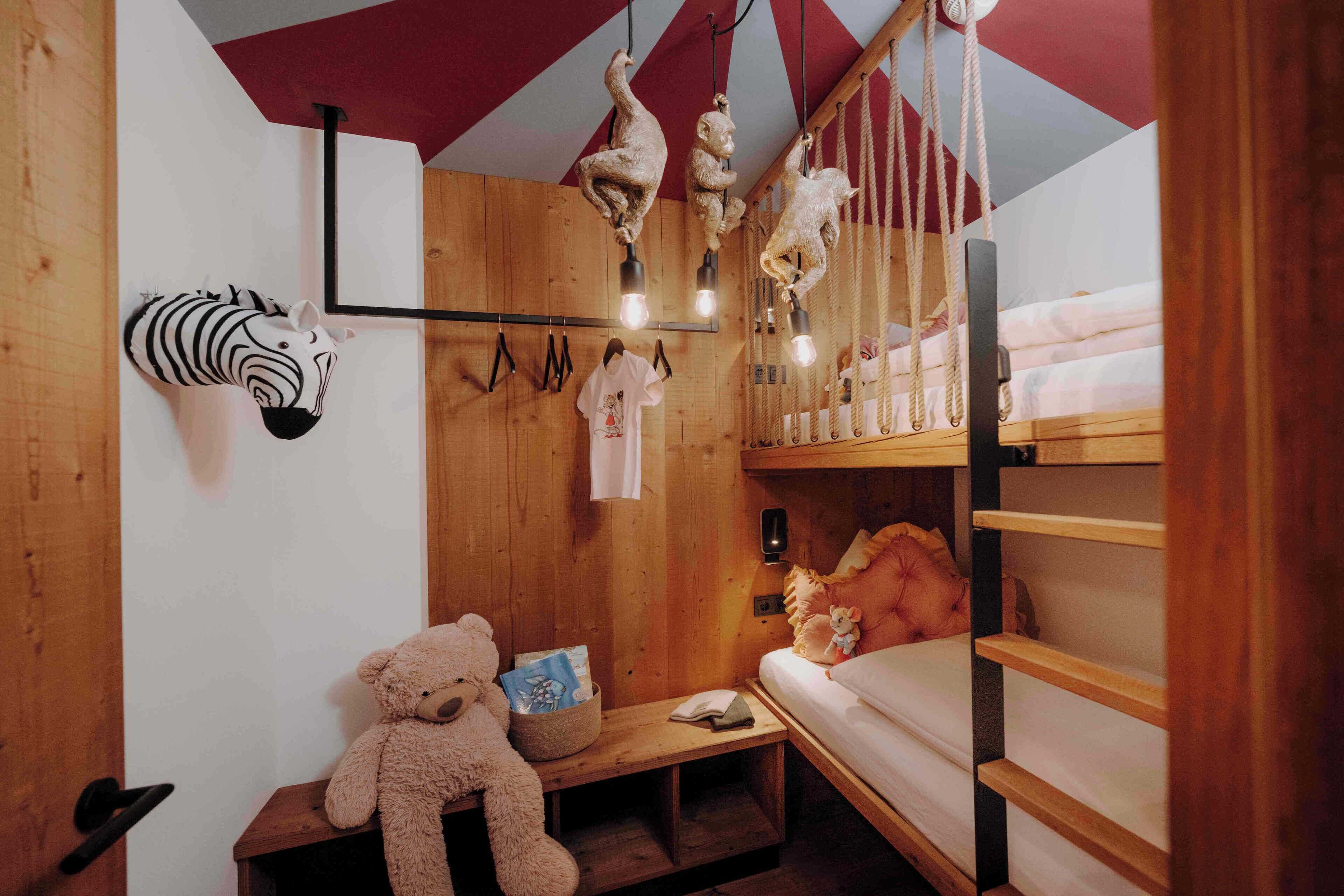 Una habitación acogedora con paredes de madera, una cama literera, un oso de peluche y una decoración con cabeza de cebra.