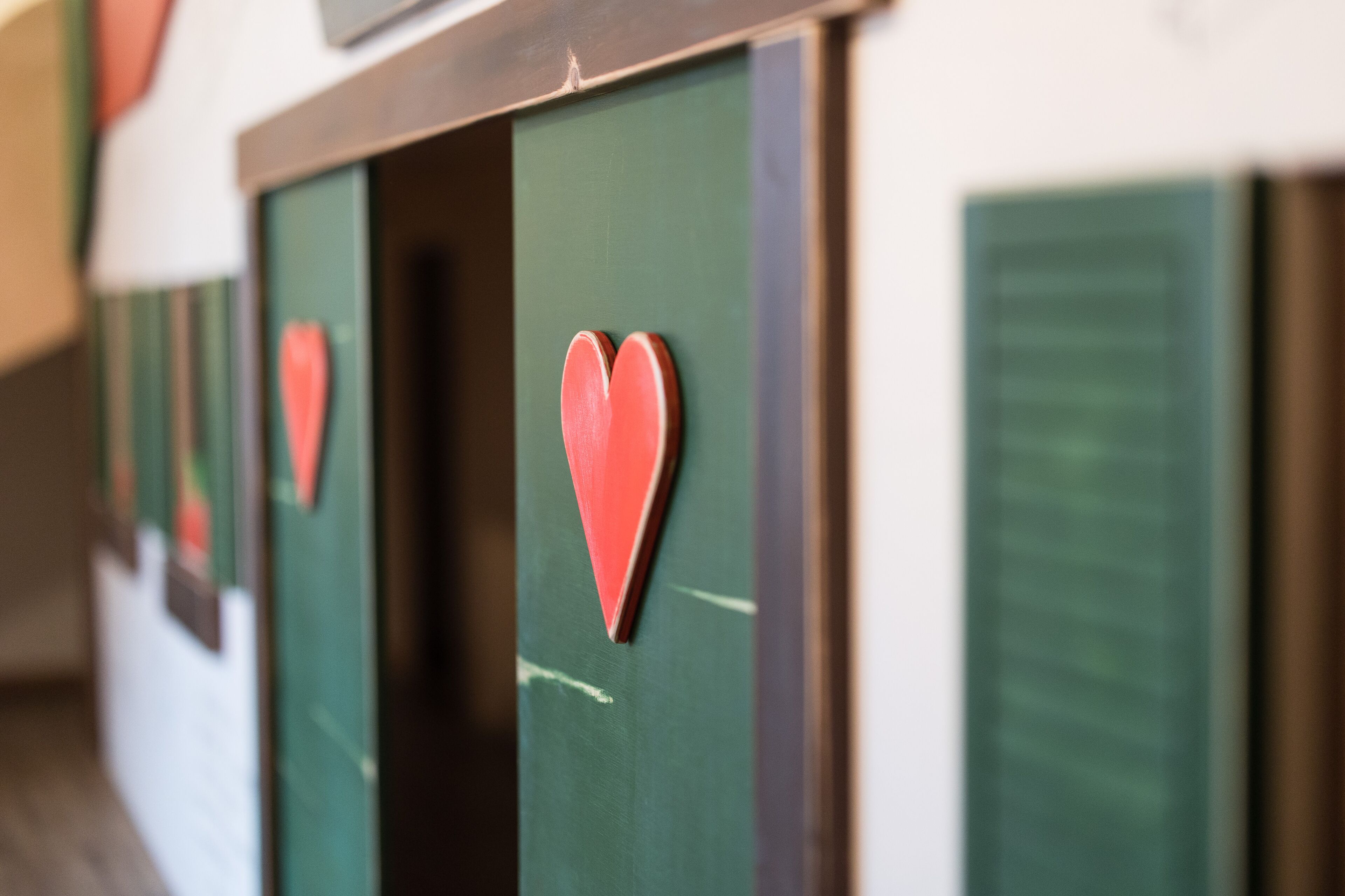 Una hilera de puertas verdes adornadas con corazones rojos.