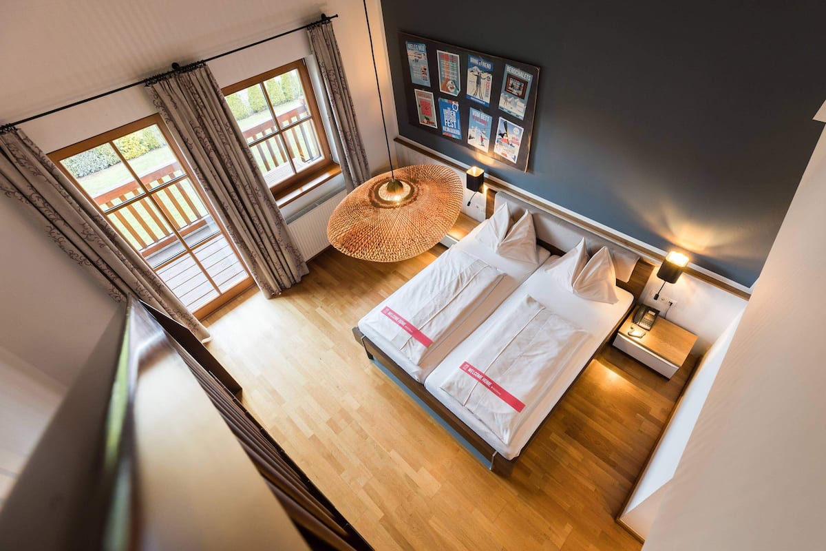 Ein Schlafzimmer mit zwei Betten, einer Pendelleuchte, einem Nachttisch und einer Wand mit Postern.