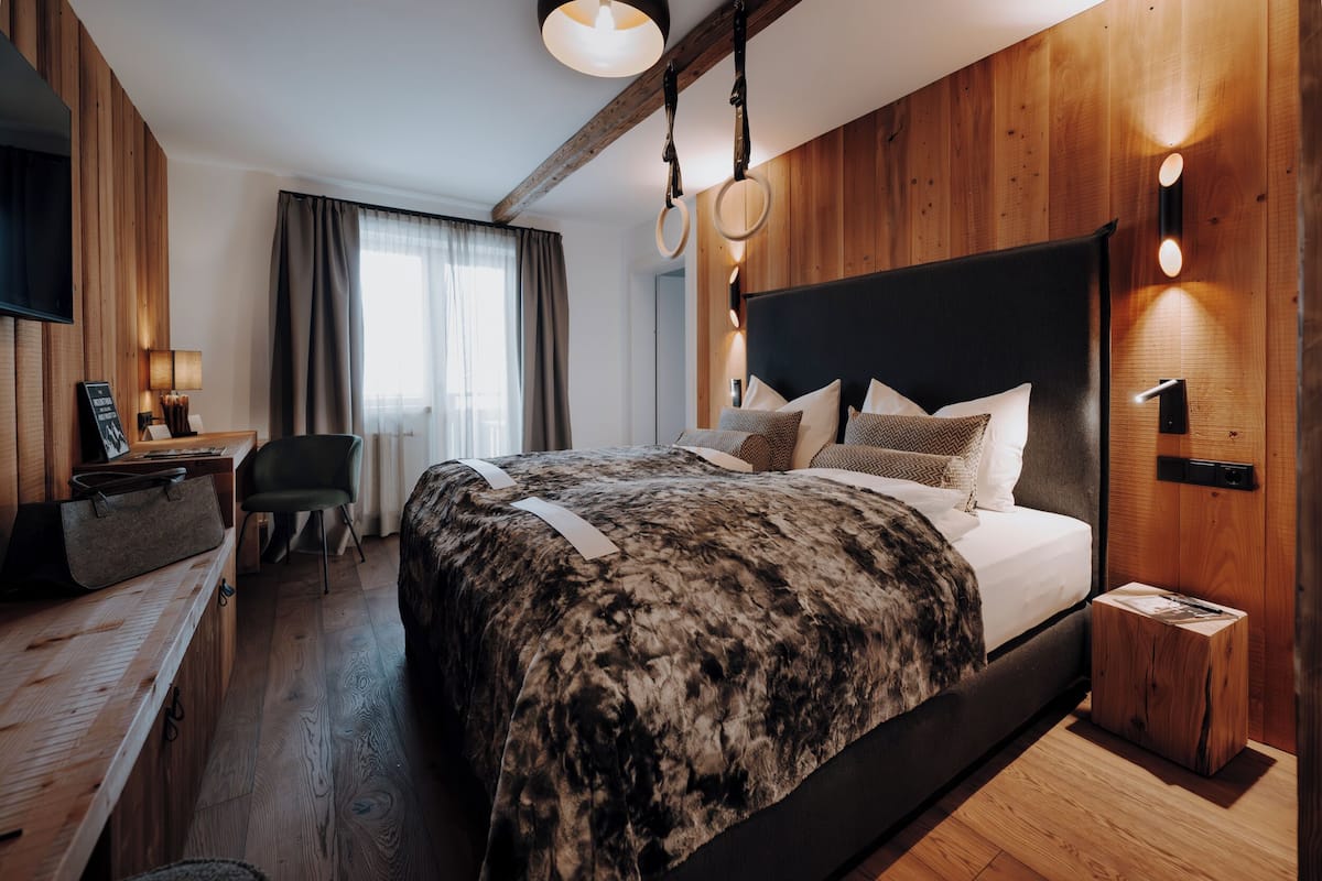 Ein modernes Hotelzimmer mit einem großen Bett, Holzwänden, einem Schreibtisch und einem Fernseher.