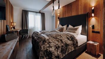 Una habitación de hotel moderna con una cama grande, paredes de madera, un escritorio y un televisor.
